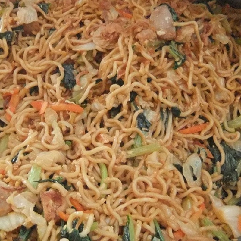 A close-up shot of seasoned stir-fried Indonesian mee goreng noodles with vegetables and shredded chicken.