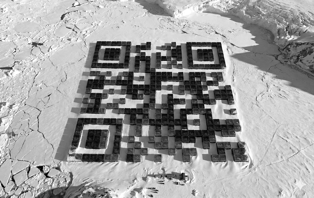 A large milk‑crate QR code arranged across snowy ground.